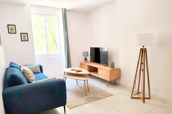 Séjour lumineux avec canapé bleu d'un appartement géré par Hostimo